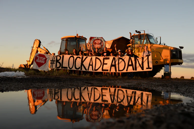 A protest group holds a sign 'Blockade Adani'