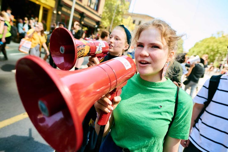 Two teenage protesters with red megaphones.