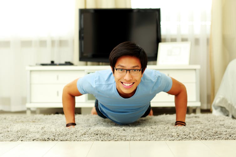 Smiling man doing pushups at home