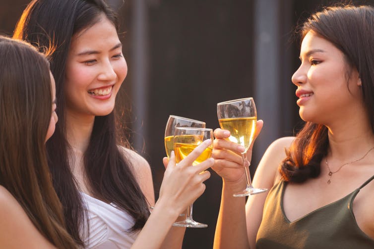 Three young people drinking wine