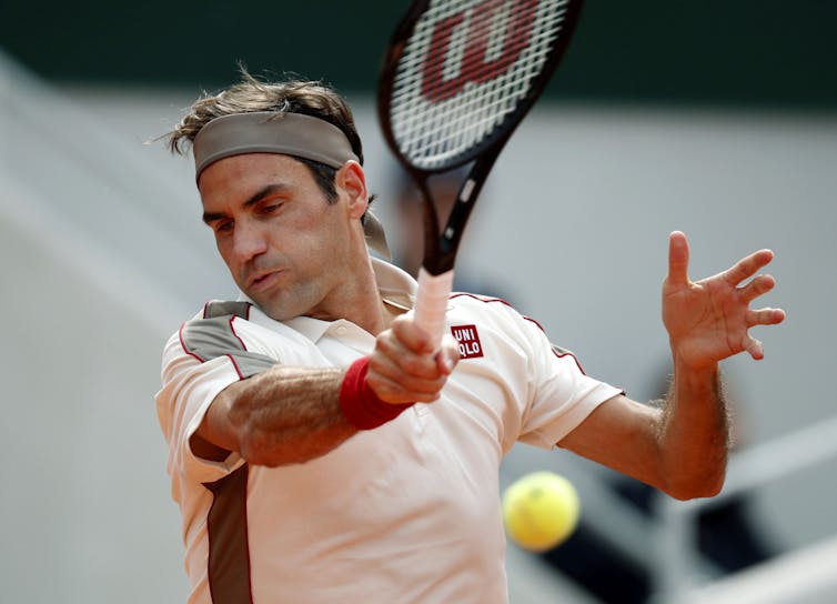 Roger Federer swinging the racket and about to hit a tennis ball.