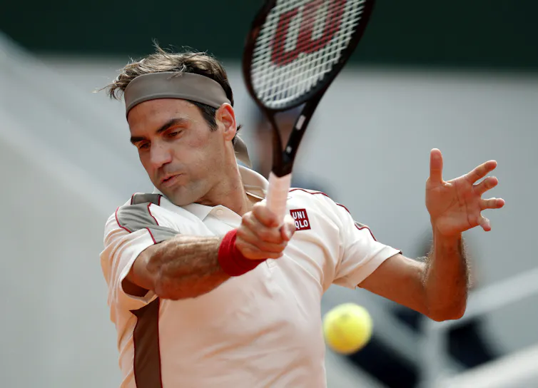 Roger Federer swinging the racket and about to hit a tennis ball.