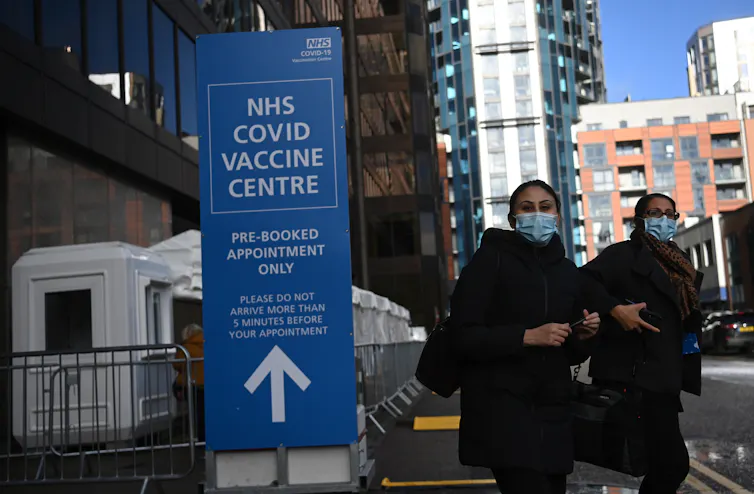 Two people leaving a UK COVID vaccination centre