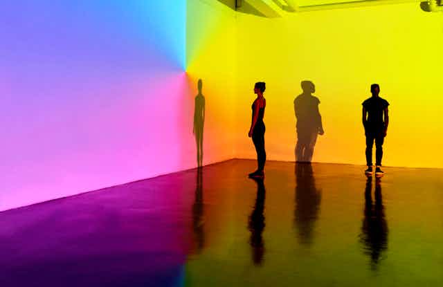 people standing in front of color projections on wall