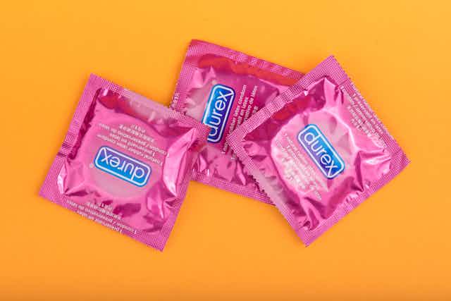 Pink Durex condom packets on an orange background.