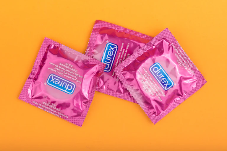 Pink Durex condom packets on an orange background.