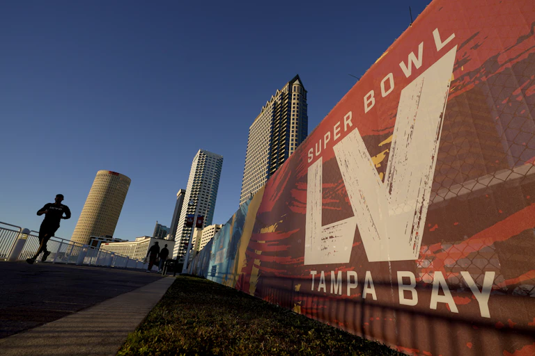 A man running past signage for the 55th Super Bowl.