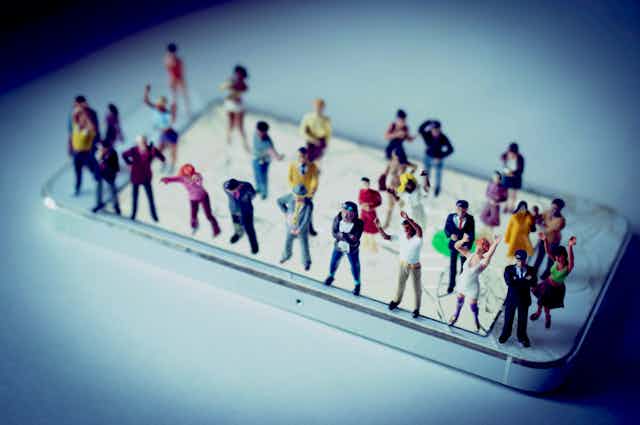 Miniature people standing on a smartphone