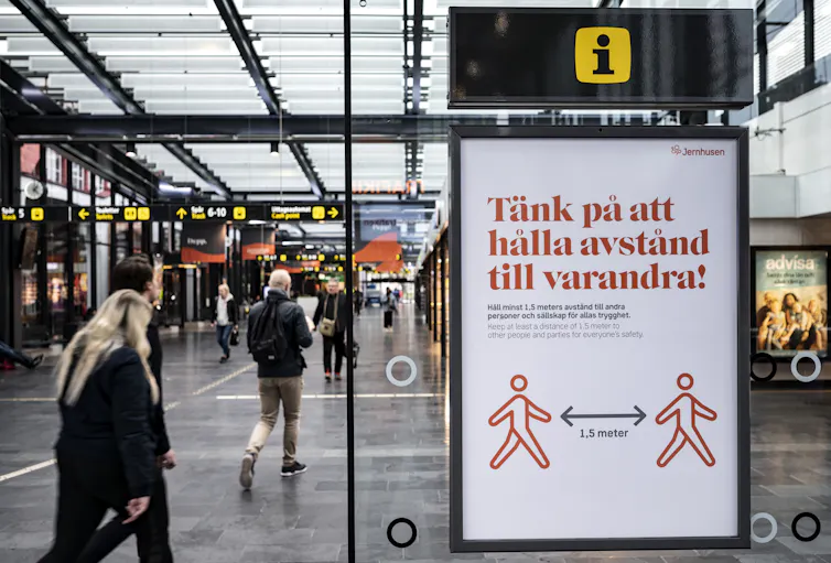 A sign at a train station encourages people to keep their distance from one another in Swedish.