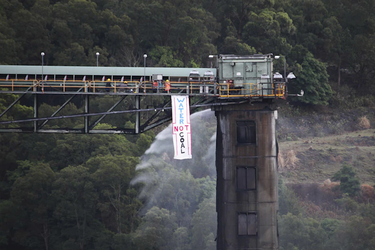 Activists unfurl banner that says "water not coal"