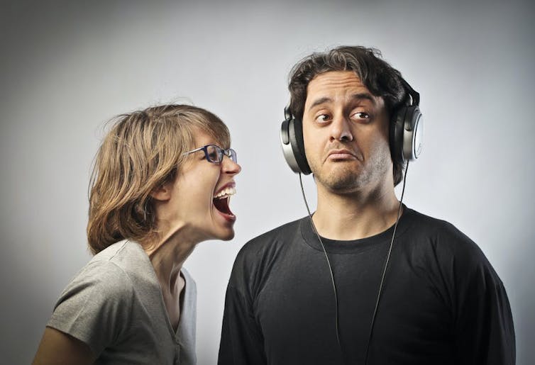 Woman yelling at a man wearing headphones and ignoring her