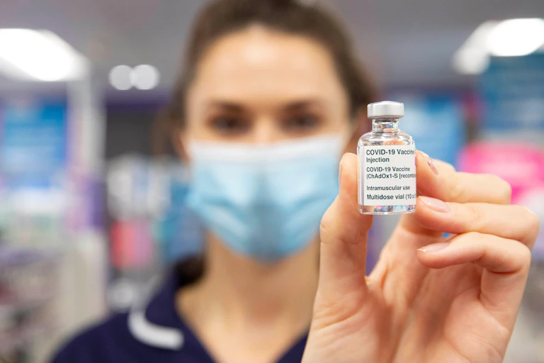 A medic holding up a vial of COVID vaccine.
