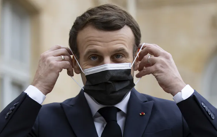 President Emmanuel Macron putting a face mask on.
