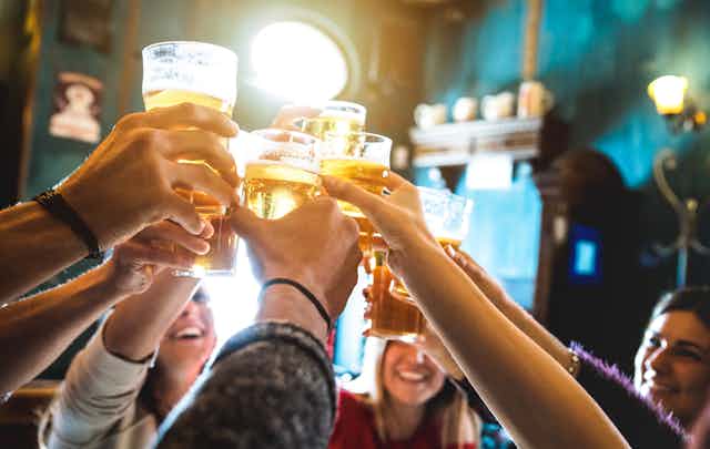 Happy people raising pints of beer in pub