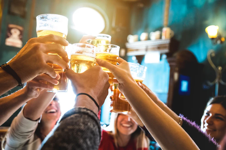 Happy people raising pints of beer in pub