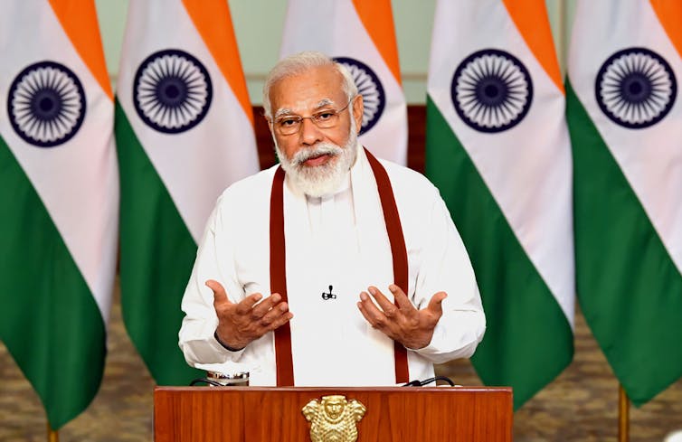 Modi giving speech in front of Indian flags