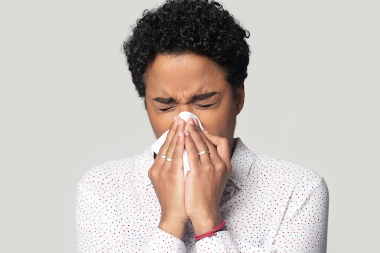 A woman sneezing into a handkerchief
