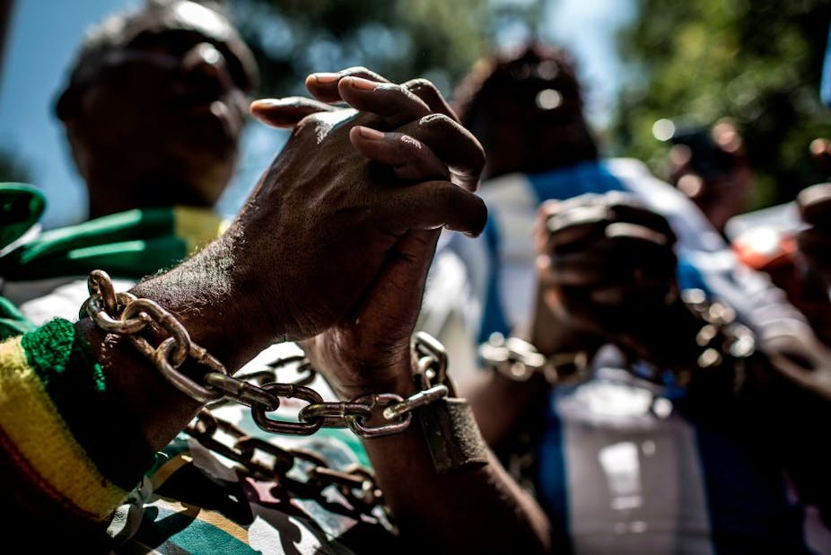 Close-up of clasped hands with chains around the wrists