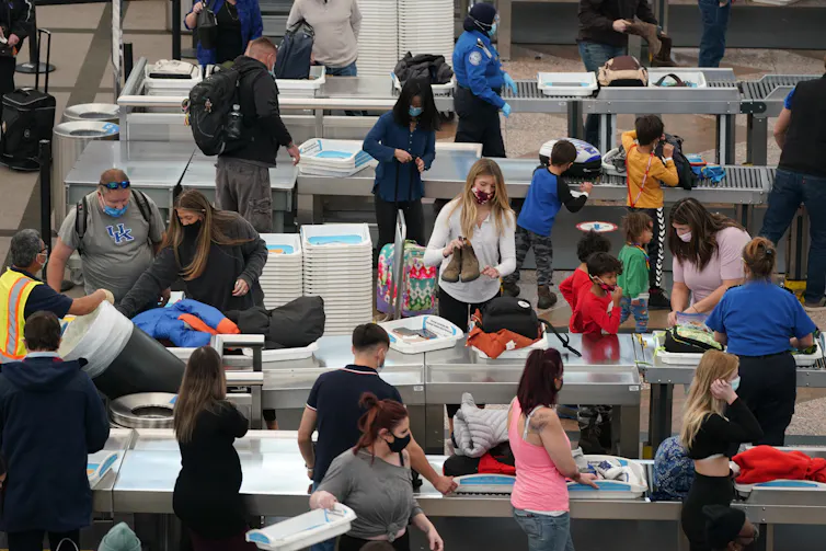Travellers wearing face masks while pass through an airport security checkpoint.