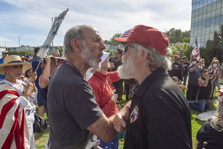 Two men at a protest about COVID-19 restrictions in California arguing with each other.