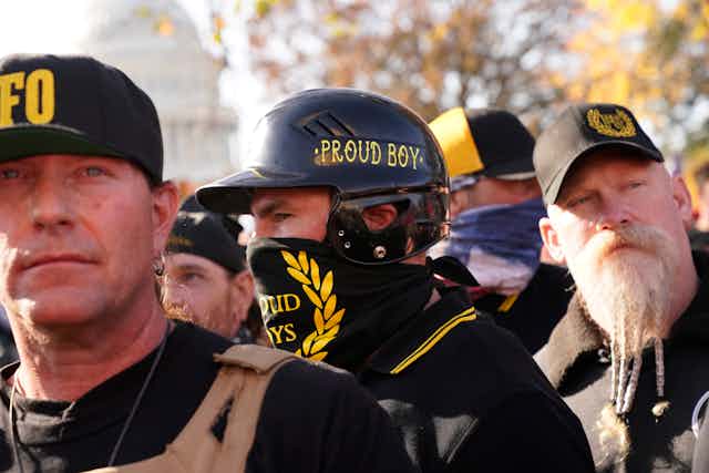 A man wearing a bandanna and hat with PROUD BOYS printed in yellow on black