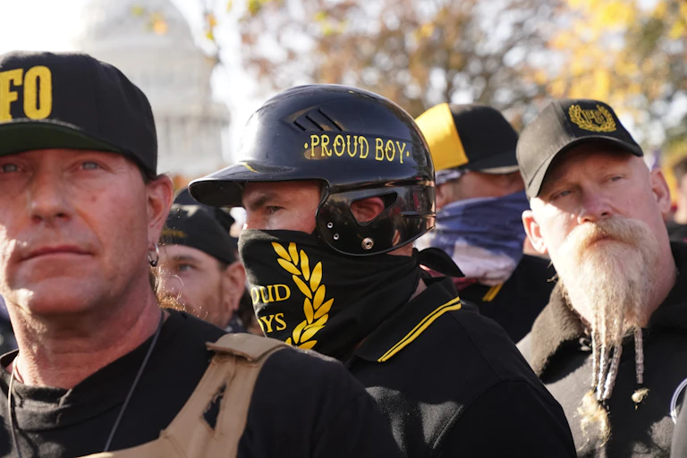 A man wearing a bandanna and hat with PROUD BOYS printed in yellow on black
