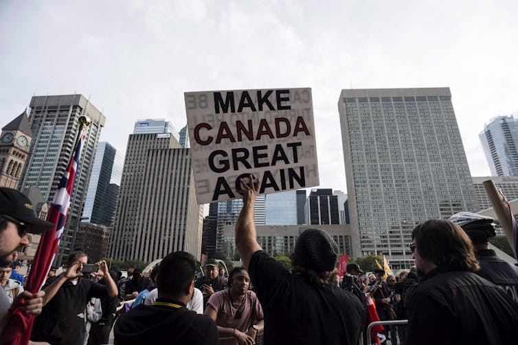 People at a protest holding a sign saying MAKE CANADA GREAT AGAIN