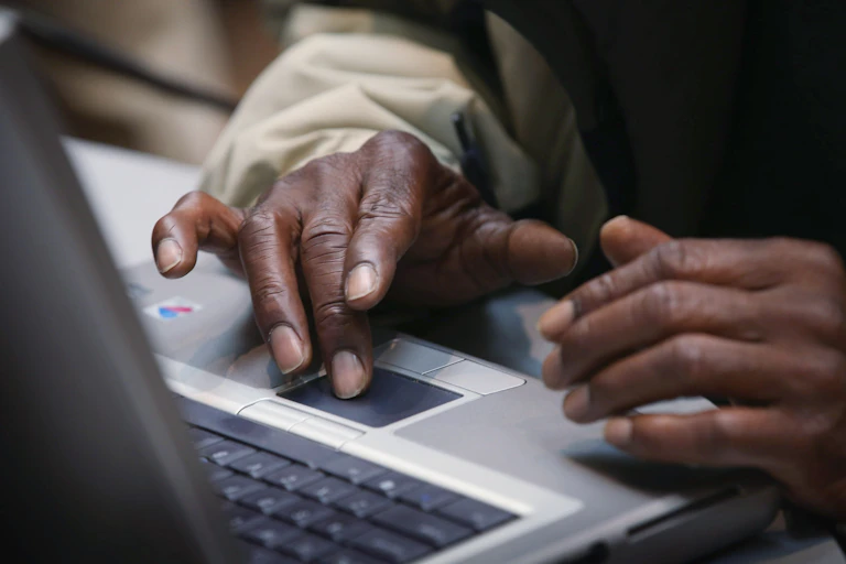 Black hands on a laptop keyboard.