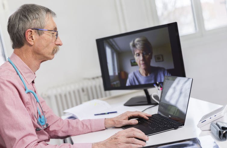 A white doctor talks to a white patient through his laptop.