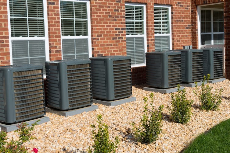 row of air conditioner units outside apartments