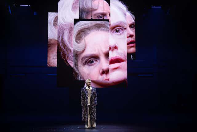 Woman onstage, with projected images behind her of her face.