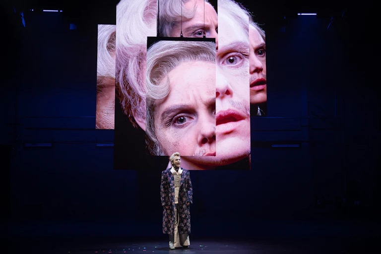 Woman onstage, with projected images behind her of her face.