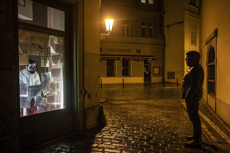 performer in shop window, man watches outside