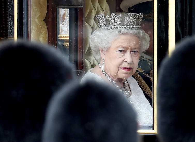 Queen Elizabeth riding in a royal carriage.