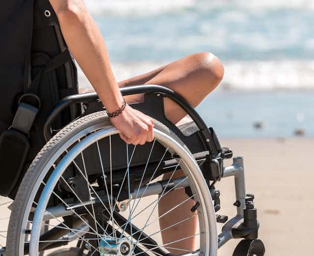 A person in a wheelchair at the seaside.