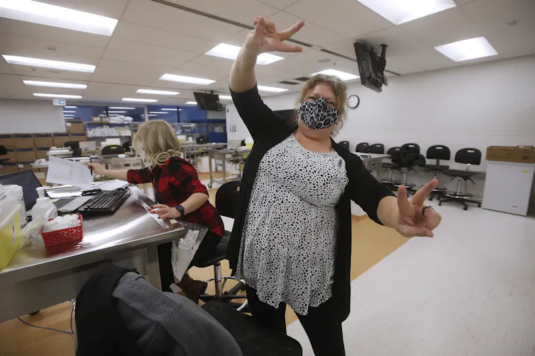 A woman in a face mask with her hands in the air in celebration.