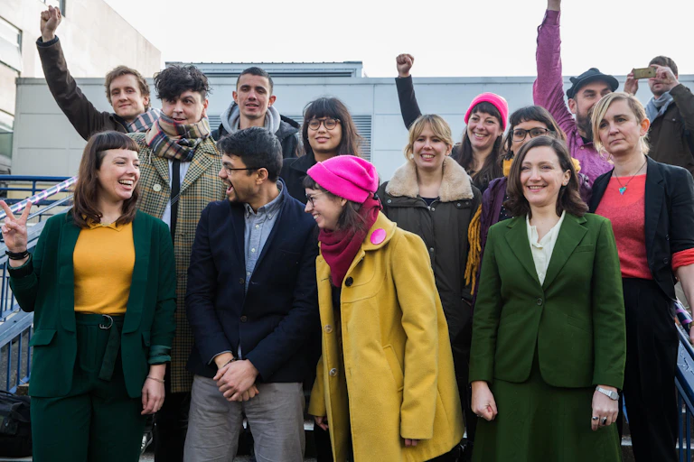 Stansted 15 standing in a group smiling and celebrating