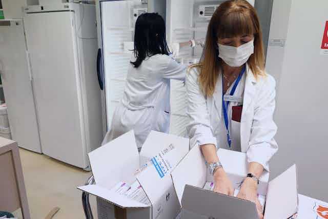 Spanish health workers filling fridges with doses of COVID vaccines