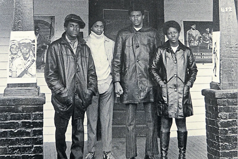 Four members of the Black Panther Party stand outside a house that served as the group's headquarters