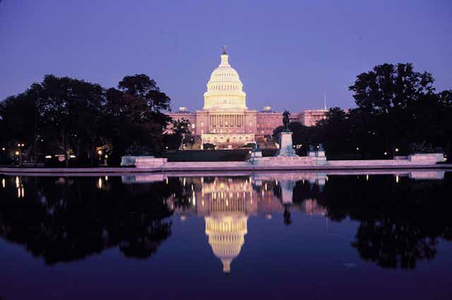 Photo of the Capitol at night with reflecting pool in the foreground