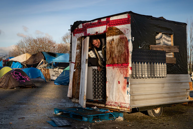 A man steps out of the trailer he lives in at a homeless encampment