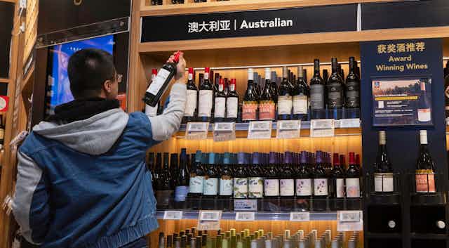 Chinese man examines an Australian wine in a bottle shop.
