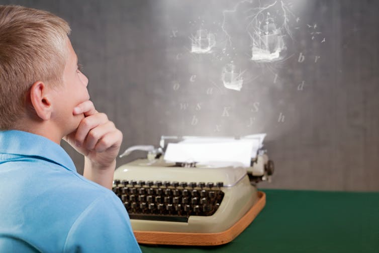A young boy at a typewriting, imagining what he will write.