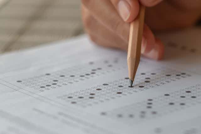 hand holding pencil over multiple choice test paper