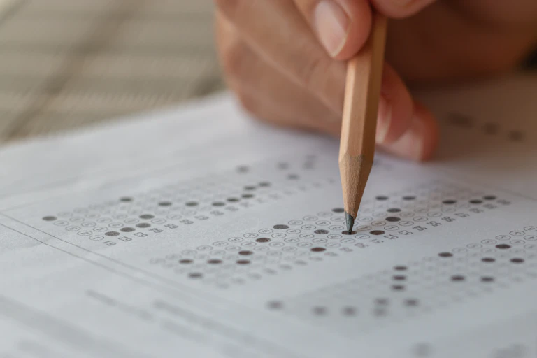 hand holding pencil over multiple choice test paper