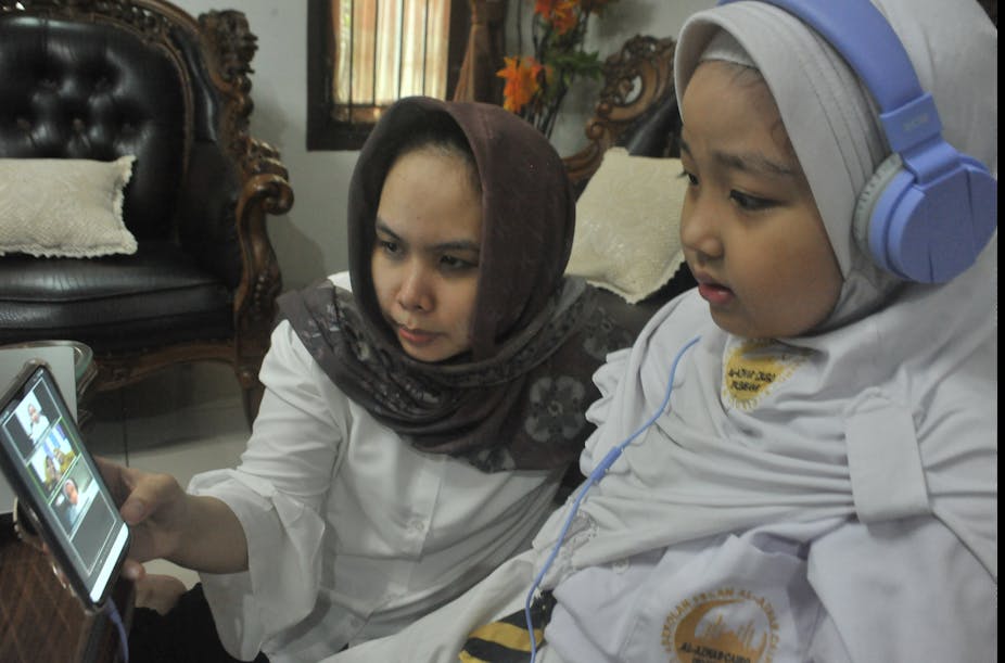 A parent accompany her child during an online learning session.