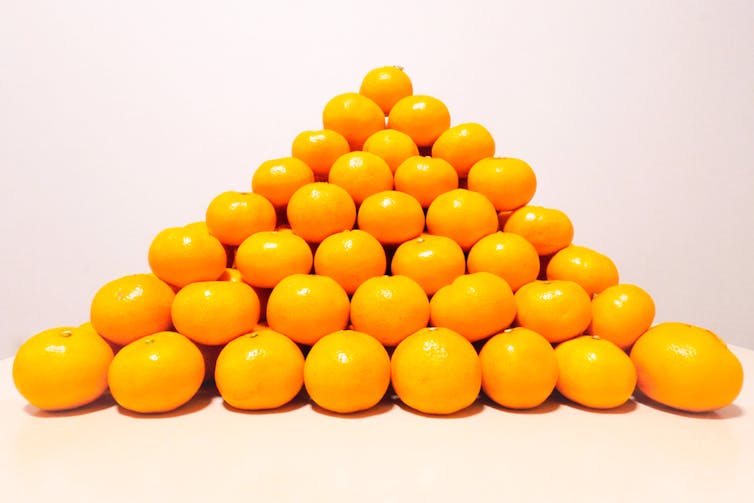 Oranges stacked up in a pyramid shape.