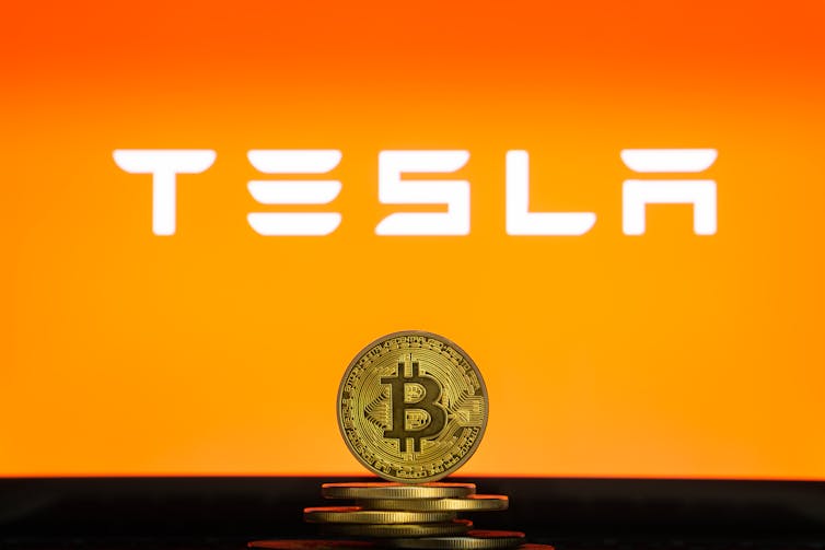 Tesls logo in front of a bitcoin
