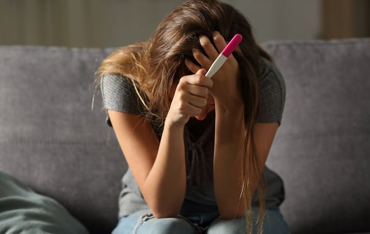 Woman holding a pregnancy test.