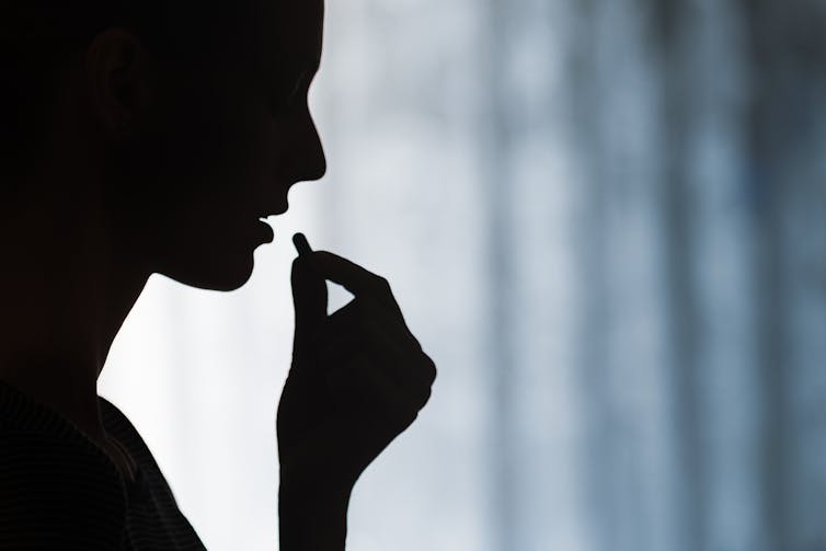 Silhouette of woman taking a pill.